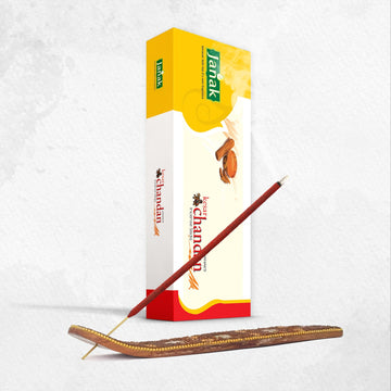 Janak Keshar Chandan Incense Sticks box beside an incense stick in a wooden holder